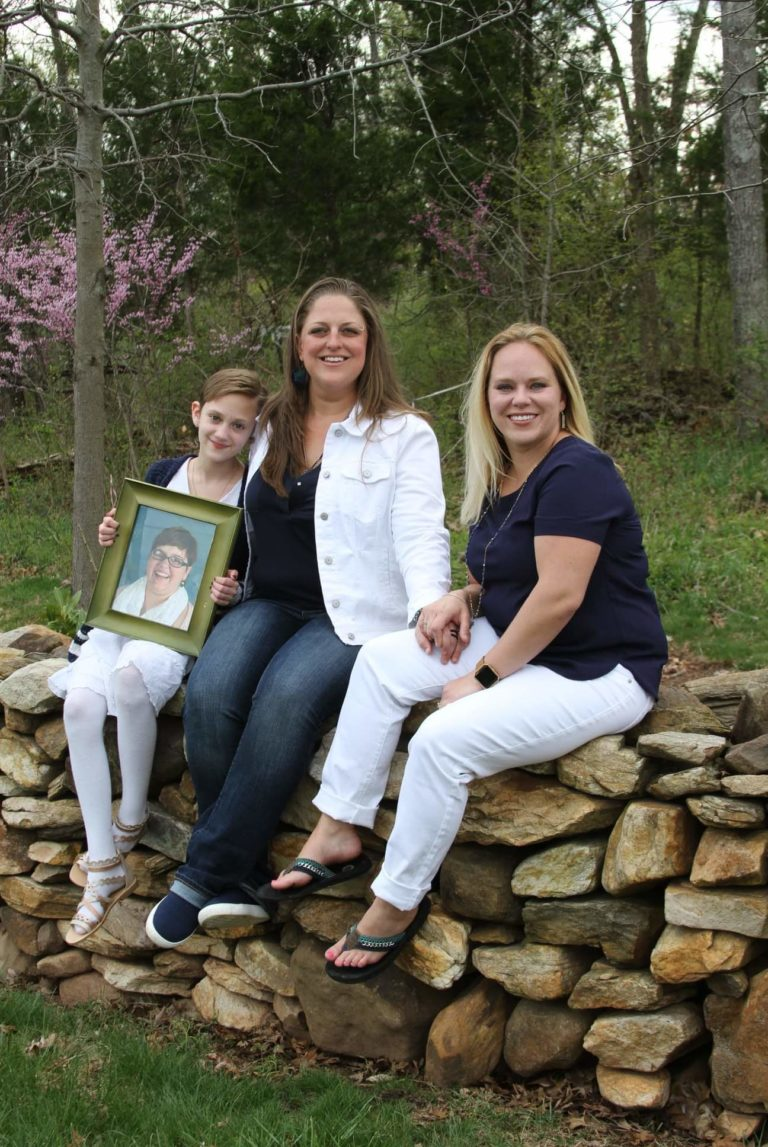 Christy, Angie, and family holding picture of Sara